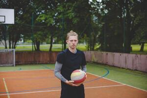 Volleyball player standing on a hard court, holding a ball with focus and determination before the game. The image captures a calm moment of preparation in an outdoor volleyball setting photo
