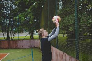 Volleyball player preparing to set the ball near the net on a hard court, focusing on precision and control. Captured from behind, showcasing outdoor volleyball skills photo