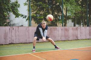 Volleyball player performing a digging on a hard court, focusing intently on the ball during an intense game. The action showcases skill, concentration, and athleticism photo