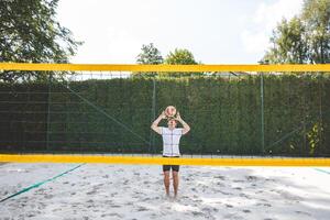 Volleyball player setting the ball on a sand court, preparing for the next play during an outdoor beach volleyball game. The action highlights control and precision in the game photo