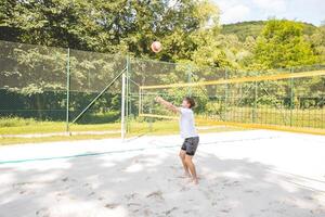 Volleyball player passing a ball on a sand court, focusing on precise ball control and technique. Captured during an intense outdoor game of beach volleyball photo