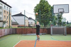 Volleyball player standing on a hard court, bouncing the ball while preparing for the next play during an outdoor game. A calm, focused moment before the action begins photo