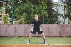 Volleyball player in a ready defensive stance on a hard court, focused and preparing to receive the ball during an intense outdoor game. The scene highlights concentration and anticipation photo