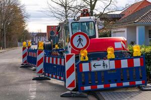 A small tractor standing on the sidewalk behind the barriers. Cabling. photo