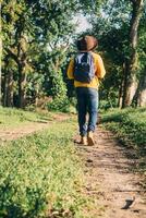 man with backpack boots and a hat walking on a path in a forest, nature travel and hiking concept. photo
