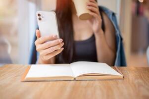 A close-up of a woman reading text messages on her smartphone while enjoying coffee in a coffee shop photo