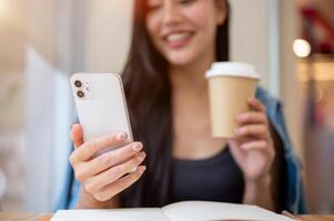 A close-up of a woman reading text messages on her smartphone while enjoying coffee in a coffee shop photo
