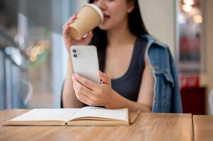 A close-up of a woman reading text messages on her smartphone while enjoying coffee in a coffee shop photo