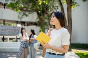 A pretty Asian female college student stands in a college park, looking away as if daydreaming. photo