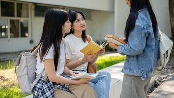 A group of female college students is discussing topics from a book in their college park. photo