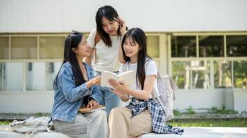 A group of Asian female college students is discussing topics from a book in their college park. photo