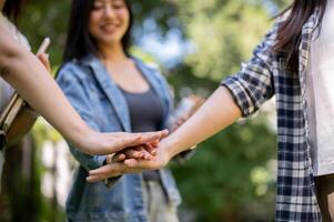 A close-up of college students putting their hands together while standing in their college park. photo