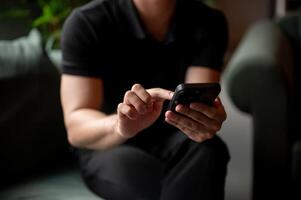 A close-up of a man using his smartphone on a sofa indoors. photo