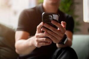 A close-up of a man using his smartphone on a sofa indoors. photo