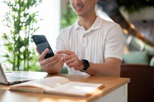 A man is reading chat messages on his smartphone while working remotely from a coffee shop. photo
