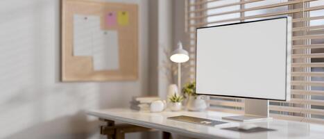 A computer with a white screen mockup on a desk against the window in a modern white office. photo