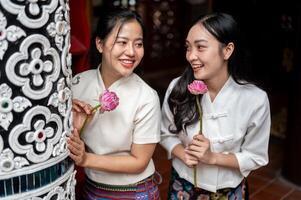 Beautiful Asian women in traditional dresses enjoy a conversation while standing in a temple. photo