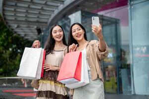 Female friends enjoy taking selfies together with a phone after their shopping spree at the mall. photo