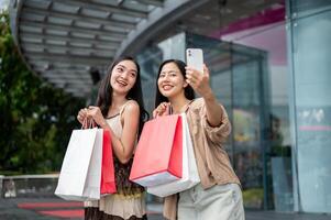 Female friends enjoy taking selfies together with a phone after their shopping spree at the mall. photo