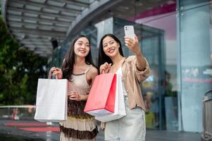 Female friends enjoy taking selfies together with a phone after their shopping spree at the mall. photo
