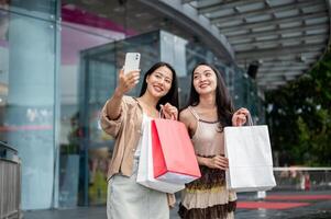 Female friends enjoy taking selfies together with a phone after their shopping spree at the mall. photo