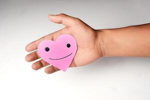 Pink heart with a happy face in the hand of a Latin man on a white background. photo