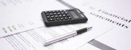 Financial statement review with calculator and pen emphasizing numbers and data analysis photo