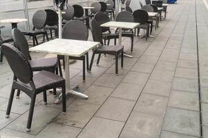 Empty outdoor cafe tables and chairs during rain photo