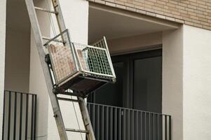 Furniture lift transporting boxes on building facade moving and relocation service photo