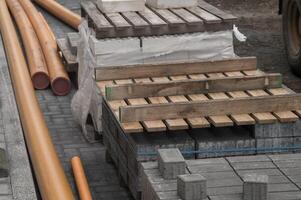 Orange pipes, paving stones and wooden pallets laying on a cobblestone street during roadworks photo