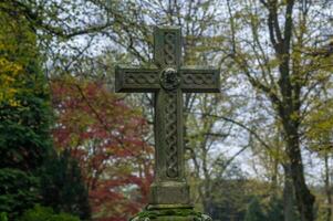 Celtic cross standing in a cemetery during autumn photo