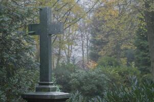 Stone cross standing in a misty cemetery in autumn photo