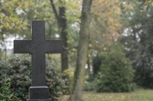 Dark stone cross standing in cemetery representing faith and remembrance photo