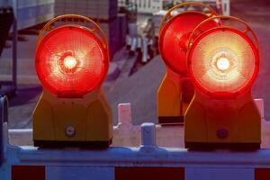 Red warning lights flashing on construction site barrier at dusk photo