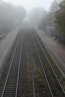 Empty train tracks disappearing into heavy fog on a gloomy autumn day photo