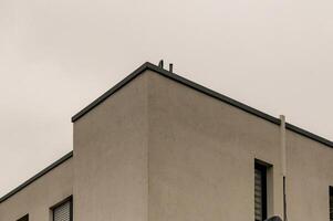 Corner of modern building reaching into cloudy sky photo