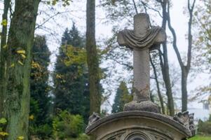 Stone cross standing on tombstone in lush cemetery photo