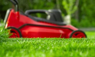 Defocused red and black lawnmower and thin focal part on the lawn. photo