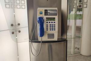 Close-up of payphone with blue handset in modern airport terminal photo