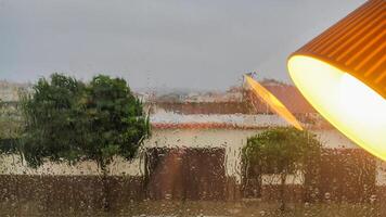 Rainy window view with warm interior lamp reflection in foreground photo