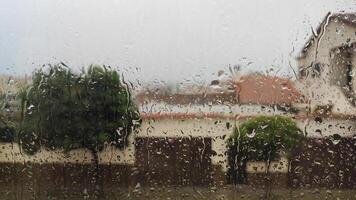 Rain-covered window view of a suburban neighborhood with blurred background photo