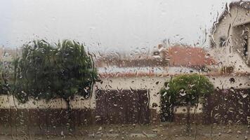 Rain-covered window view of a suburban neighborhood with blurred background photo