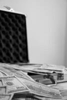 A black and white image of an open metal briefcase with stacks of cash spilling out photo