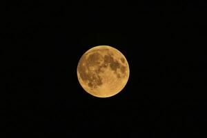 The full moon is seen in the dark sky photo