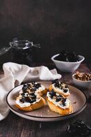 Delicious toasts with ricotta and prunes on a plate on the table web banner vertical view photo