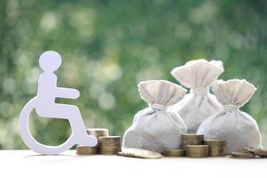 Man on wheelchair and coin money on natural green background,Save money for prepare in future and handicapped person concept photo