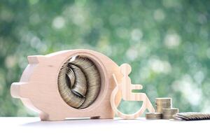 Man on wheelchair and piggy bank on natural green background,Save money for prepare in future and handicapped person concept photo
