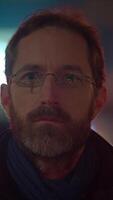 A man in glasses stands against a captivating urban night background, creating a profound vibe video