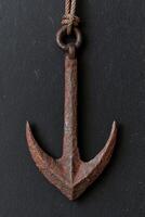 Rusty anchor hanging on rope photo