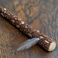 Rustic wooden stick with feather on table photo